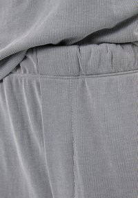 Grau-weiß gestreifter Stoff mit einer subtilen Textur, ausgestattet mit einem elastischen Bund und sauberen Nähten an den Säumen.