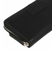 Portefeuille en cuir noir avec une finition texturée, doté d'une fermeture éclair et d'une étiquette en argent. Forme rectangulaire compacte pour un transport facile.