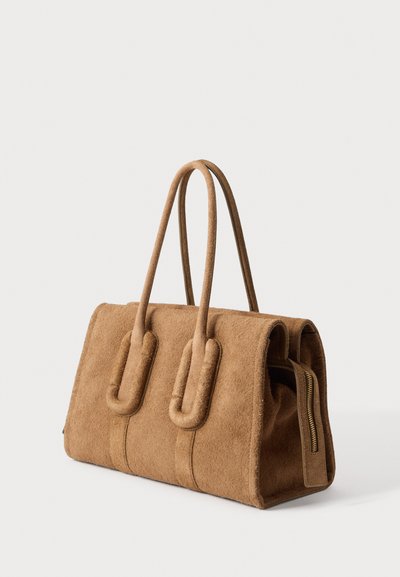 Sac à main en daim marron avec deux poignées arrondies et une fermeture éclair latérale visible, sur un fond clair uni.