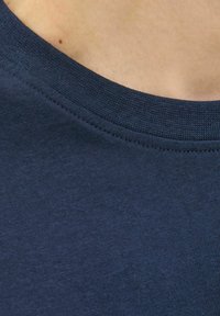 Tumesinine T-särk, millel on ümar kaelus ja peen sooniline tekstuur. Kangas näeb välja pehme, ühtlane kudumimuster.