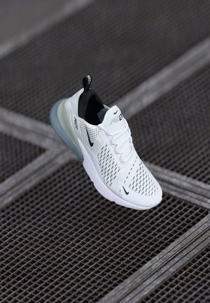 Valkoinen Nike Air Max 270 -lenkkari mustilla yksityiskohdilla, verkkopäällisellä ja läpikuultavalla sinisellä pohjalla metalliritiläpinnalla.