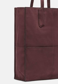 Bordowa torba na ramię ze skóry o gładkiej fakturze, prostokątnym kształcie, kontrastujących czarnych szwach, górnych uchwytach i minimalistycznym designie.