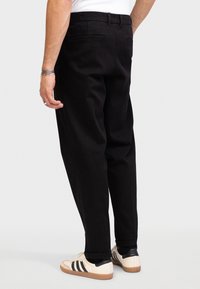 Pantalones negros de corte recto, confeccionados en una tela suave. Incluyen bolsillos traseros y un cinturón para un cierre seguro.