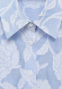 Chemise à rayures bleues et blanches avec un motif floral texturé, dotée d'un col pointu et de cinq boutons de fermeture.