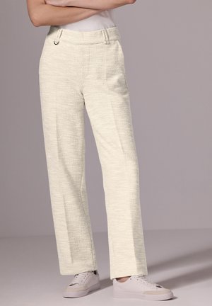 Crème kleurige wijde broek met een textuurstof, voorzien van zijzakken en een stijlvolle tailleband, gecombineerd met witte sneakers.