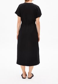 Czarna sukienka do kolan z krótkimi rękawami i elastyczną talią. Wykonana z gładkiego materiału, ma prostą sylwetkę bez widocznych wzorów.