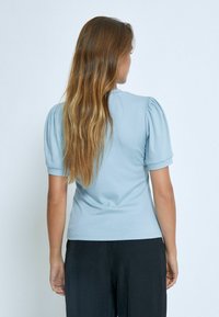 Gaiši zils ribotas t-krekls ar īsām puff piedurknēm, pieguļošs dizains, gluda tekstūra un apaļa apkakle, apvienots ar melnām biksēm.