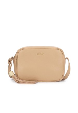 Smėlio spalvos odinė per petį nešiojama rankinė su auksiniu „kazar“ logotipu, apvaliais kampais, reguliuojama dirželiu ir dekoratyviniu kutu su auksiniu akcentu ant balto fono.