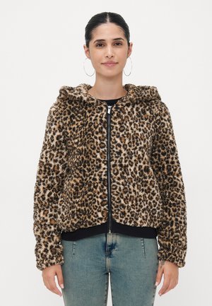 Leopardenmuster Zip-Hoodie aus weichem, strukturiertem, braunem und schwarzem Kunstfell, mit Kapuze sowie gerippten Bündchen und Saum. Kombiniert mit hellblauen Jeans.