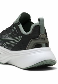 Chaussure de sport noire avec une tige texturée, accents en vert menthe, semelle blanche épaisse et contrefort renforcé. Dotée d'une languette pour un enfilage facile.