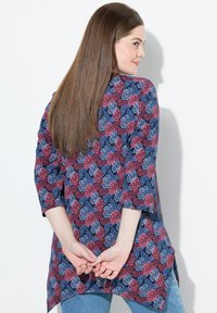 Marineblaues Tunika mit floralem Muster in Rot und Blau, mit Dreiviertelärmeln, abgerundetem Saum und leichtem Stoff.