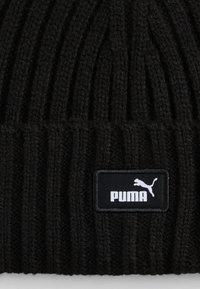 Berretto in maglia nera con texture a coste, dotato di una patch rettangolare nera con il logo e l'icona bianchi "PUMA" sul davanti.