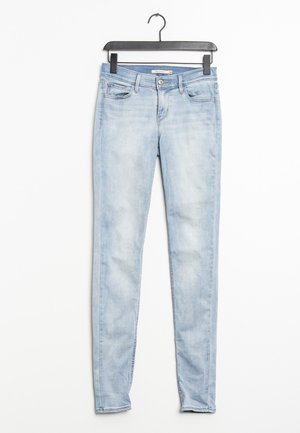 Ljusblåa skinny jeans av denim med midjepassning, framfickor och blekt utseende. Hänger på en svart plastgalge.