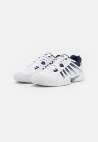 White athletic shoes with a textured upper, navy accents, and multiple racing stripes. Features laces and a rubber sole for grip.