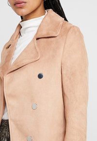 Tan faux suede dubbele knopenjas met schouderkraag en zilverkleurige knopen, met een gladde textuur en een getailleerde pasvorm.