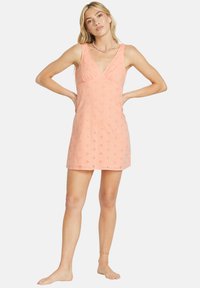 Peach cotton sundress with a V-neck, sleeveless design, embroidered floral patterns, and a relaxed fit, reaching mid-thigh length.