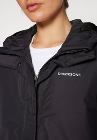 Schwarze wasserdichte Jacke mit Reißverschluss, hohem Kragen und Logodetail. Verfügt über eine glatte Textur und eine praktische Kapuze.