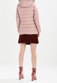 Light pink puffer jacket with horizontal quilted design, fur-lined hood, worn over a brown skirt and pink velvet ankle boots. Smooth texture.