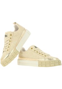 Sneakers crema con tomaia in tessuto testurizzato, dettagli metallici dorati e una suola bianca spessa con motivi a quadrato.