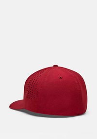 Gorra de béisbol roja con forma estructurada, que presenta una tela texturizada y un diseño perforado en la parte posterior para ventilación. Visera plana.