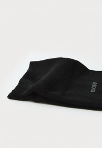 Schwarze Baumwollsocke mit einem strukturierten Strickmuster, ausgestattet mit einem umgeschlagenen Bund und dezentem Branding in Grau in der Nähe der Zehenpartie.