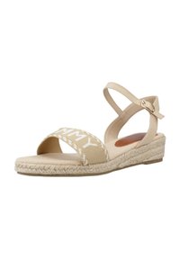 Beige espadrille sandaal met een geweven jute zool, een elastische enkelband en een bovenwerk van canvas met witte tekst.
