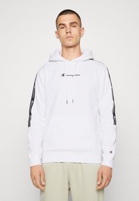 Felpa bianca con tasca a marsupio frontale, cappuccio con cordino e logo nero. Presenta strisce nere con il marchio lungo le maniche. Materiale in cotone.