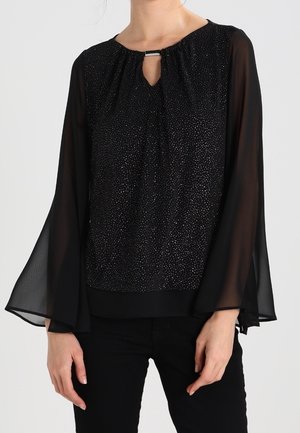 Czarna bluzka z przezroczystymi długimi rękawami w kształcie dzwonka, małym dekoltem z wycięciem typu keyhole z metalowym zapięciem i subtelnym błyszczącym kropkowanym wzorem na przodzie.