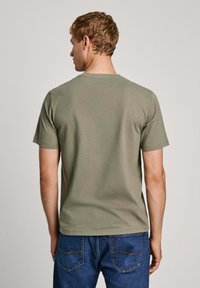 T-shirt a maniche corte verde khaki realizzato in cotone, con colletto rotondo e una texture liscia, mostrato da dietro.