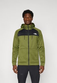Groene hoodie met zwarte accenten, volledige ritssluiting aan de voorkant en voorzakken. Glad materiaal met verstelbare koorden op de capuchon.