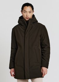 Cappotto verde scuro con cappuccio e silhouette dritta, dotato di due tasche laterali e una texture morbida. Davanti chiuso con dettagli hardware minimi.