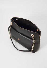 Borsa a tracolla in pelle nera con chiusura a zip, dotata di un pannello frontale liscio, dettagli in catena dorata e tracolla rimovibile.