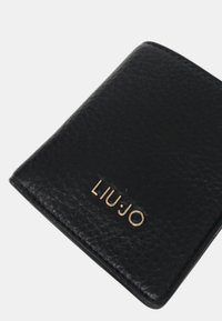 Portafoglio in pelle nera con finitura testurizzata, con logo dorato "LIU·JO" sul fronte. Design compatto con angoli arrotondati.
