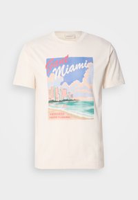 Kreem värvi puuvillane t-särk, millel on graafiline trükk Miami siluetist, lainetest ja pilvedest pastelsetes värvustes, koos tekstiga "GANT Miami" ja "Tervitused Floridast".