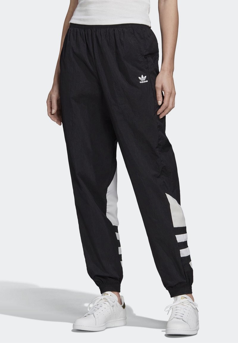 Svarta lätta träningsbyxor med elastisk midja, vita sidopartier och tre vita ränder längs de nedre benen.