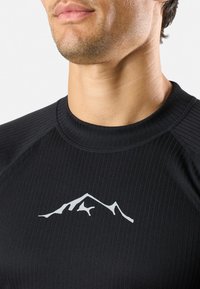 Schwarz, geripptes Sportshirt mit einem weißen Berggrafik auf der Brust und einem runden Halsausschnitt. Glatte Textur mit figurbetontem Design.