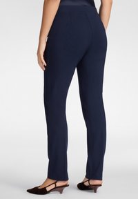 Pantalones de marino hechos de una tela suave, con un diseño ajustado, piernas rectas y una cinturilla sencilla, combinados con zapatos de tacón marrones.