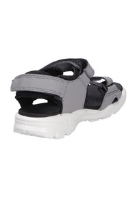 Sandale de sport grise et noire avec des sangles ajustables et une semelle blanche épaisse, vue de dos et de côté sur fond blanc.