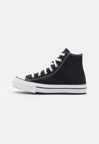 Sorte high-top joggesko laget av lerret med hvite lisser, gummitåhette, hvit såle og svarte og hvite striper langs den nederste kanten.