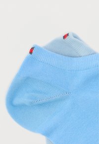 Ανοιχτό μπλε βαμβακερό καλτσάκι με ριμπ μανσέτα και μικρές κόκκινες και μαύρες λεπτομέρειες στην κορυφή. Μαλακή υφή με ομαλή επιφάνεια.