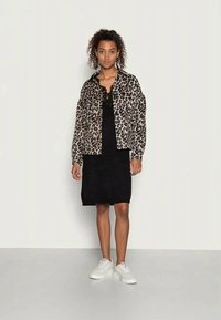 Lepardmönstrad jacka, svart ribbad klänning och vita sneakers. Mjuk tyg, oversized passform och detaljerad med spetskant på klänningen.