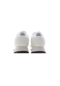 Zapatillas deportivas blancas con acentos de ante y una suela texturizada. El tacón muestra "DESDE 1890" en letras negras. Diseño aerodinámico.