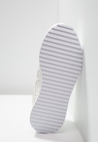 Vit sneakersula med en texturerad, räfflad mönstring. Materialet verkar gummiaktigt. Ren design med minimala detaljer och släta kanter.