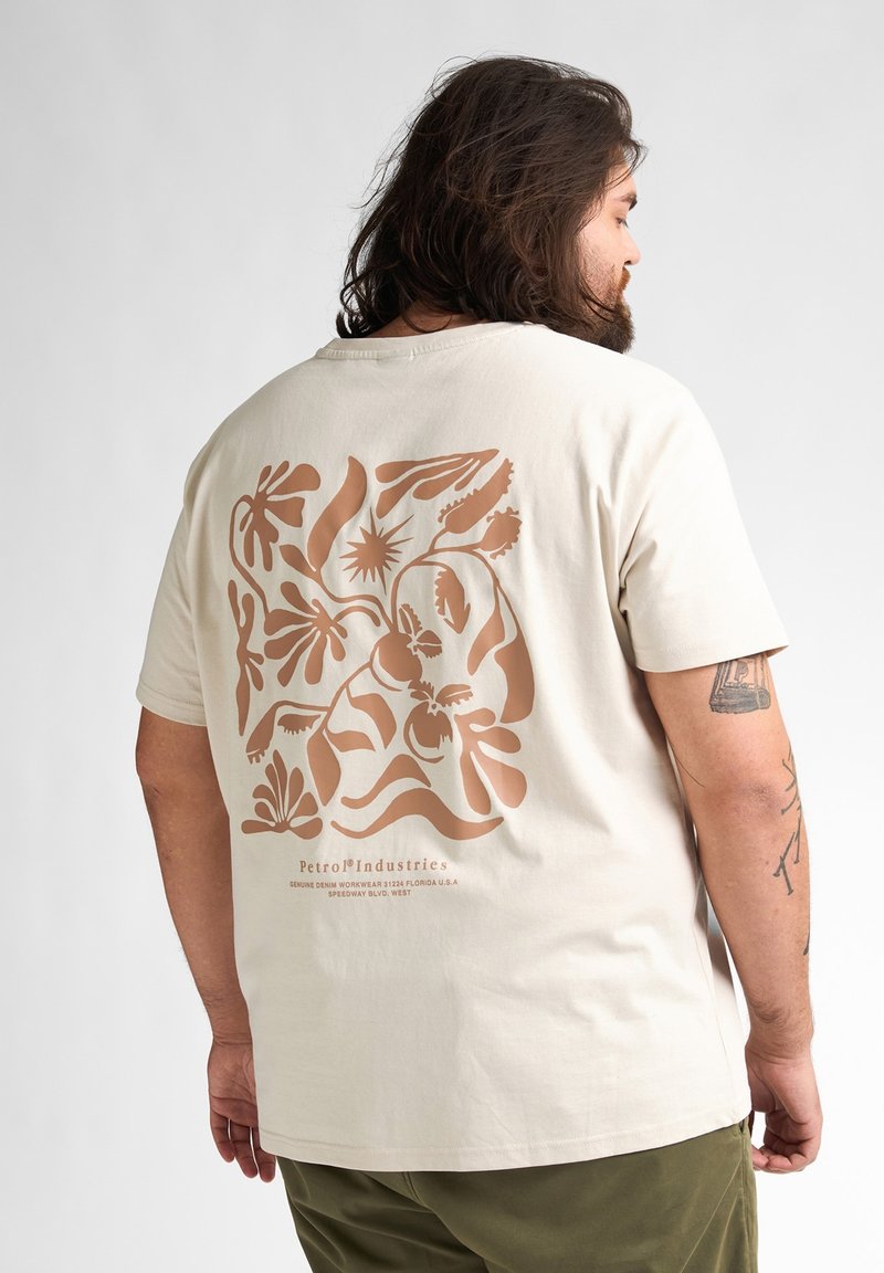 Beige T-shirt met een groot bruin bloemenontwerp op de rug, korte mouwen en een relaxte pasvorm, gemaakt van zacht katoen.