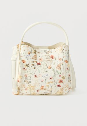 Cremefarvet håndtaske med blomstermønster og sommerfugleprint, enkelt håndtag og justerbar skulderrem, sat mod en ensfarvet baggrund.