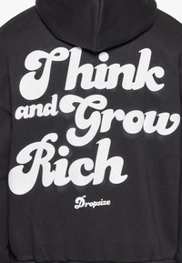 Sort hættejakke med stor hvid tekst, der står "Think and Grow Rich" og brandnavnet "Dropsize" i mindre tekst nedenfor.
