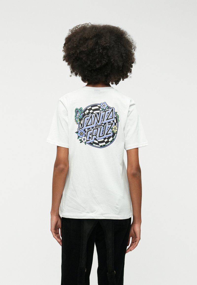 Biela tričko s farebnou grafikou na chrbte, na ktorej je napísané "Santa Cruz", spolu s motýľmi a kvetmi na šachovnicovom pozadí.