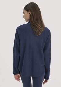 Pullover in felpa blu navy con vestibilità rilassata, collo a coste e maniche raglan; texture morbida con un orlo posteriore leggermente più lungo.