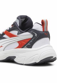 Bílé tenisky s šedými a oranžovými akcenty, síťovaným svrškem, texturovanými doplňky, polstrovaným límcem a zadním poutkem pro snadný přístup.