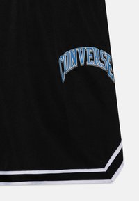 Shorts sportivi neri con un logo "CONVERSE" curvo blu e bianco. Presentano strisce bianche e nere all'orlo inferiore. Texture liscia.